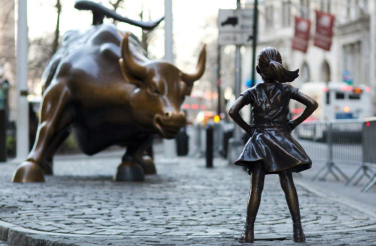 Image of a young girl staring down the Charging Bull structure.