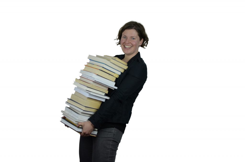 Image of a smiling woman carrying lots of books