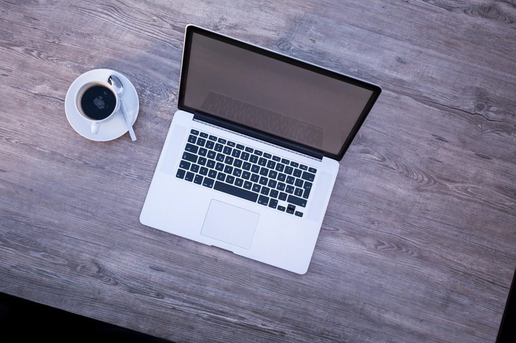 Image that shows a MacBook Air on a table with a cup of coffee next to it. 