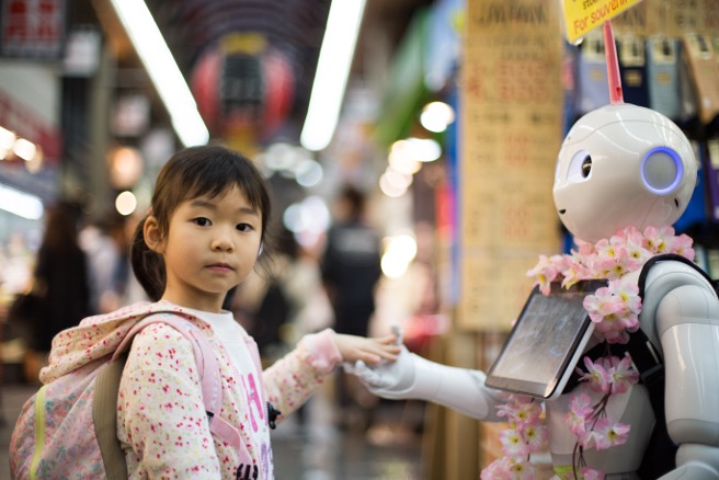photo of a child holding hands with a robot