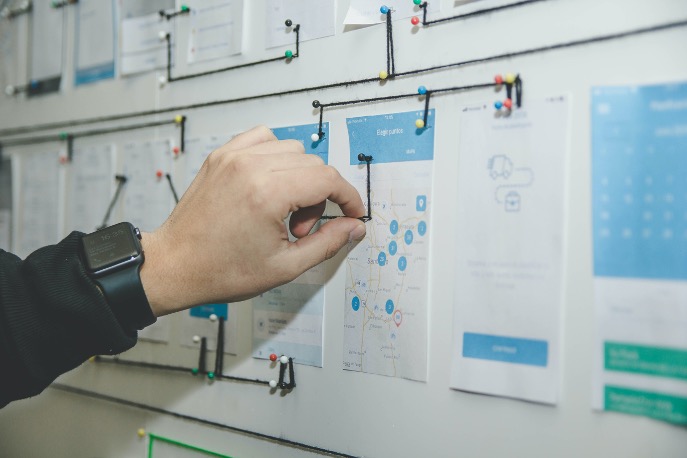 Image of a hand connecting printed out wireframes